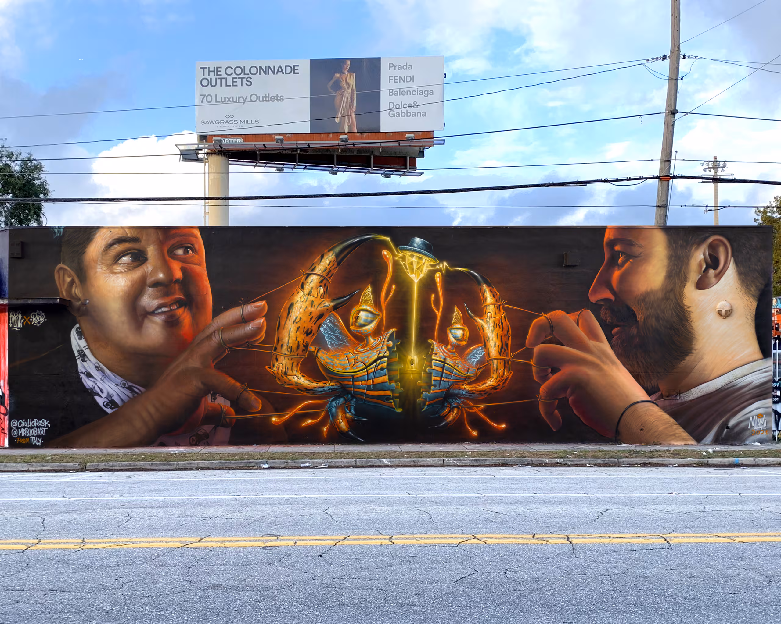 Stunning street art mural in Wynwood, Miami by Mr Blob and Giulio Rosk, featuring two hyperrealistic portraits facing a central surreal biomechanical character connected by glowing lines.